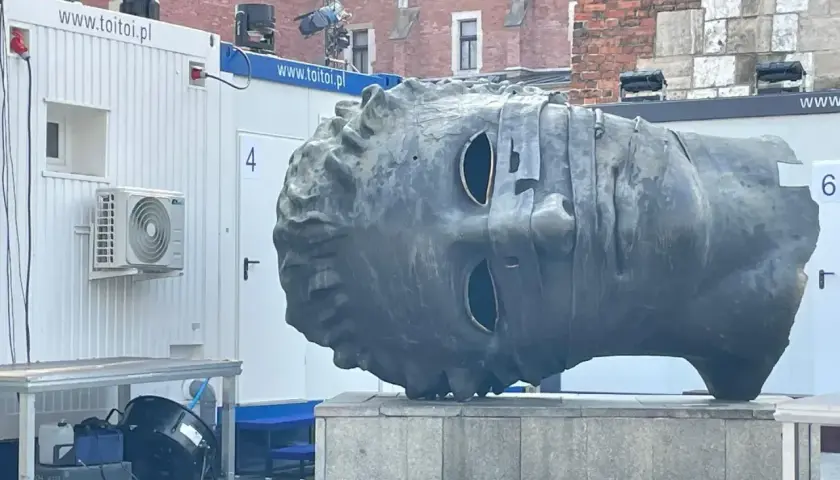 Monumentalna głowa na rynku w Krakowie, z pustymi oczodołami, wygląda jakby patrzyła w dal.