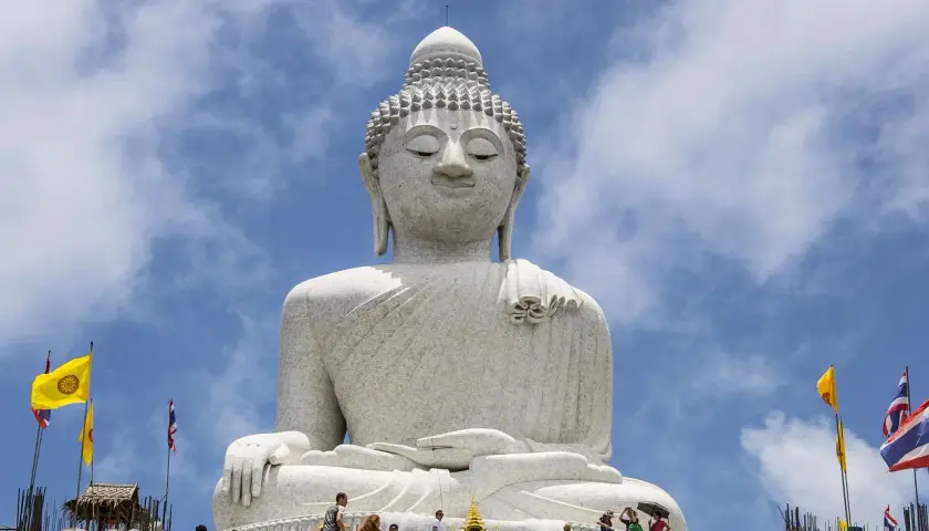 Wielki Budda na Phuket, majestatyczna biała statua na tle błękitnego nieba z chmurami. Turyści wchodzą po schodach.