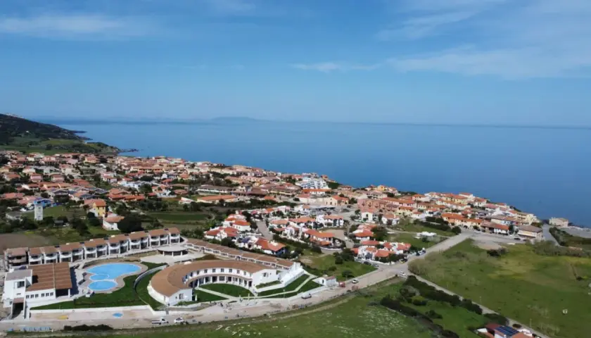 Widok z lotu ptaka na kurort GH Santina Resort z basenem i budynkami, nad morzem na Sardynii.
