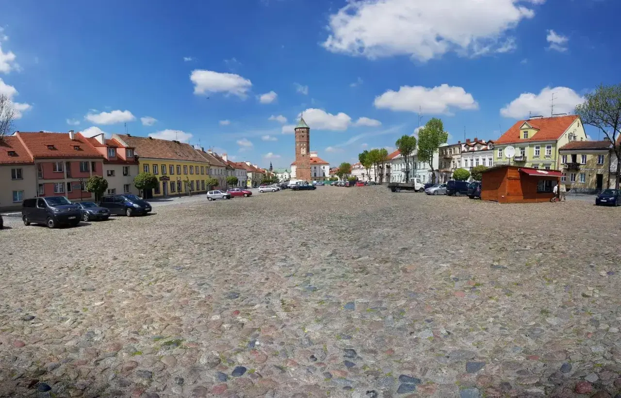 Rynek w Pułtusku z brukowaną nawierzchnią, kolorowymi kamienicami i charakterystyczną wieżą.