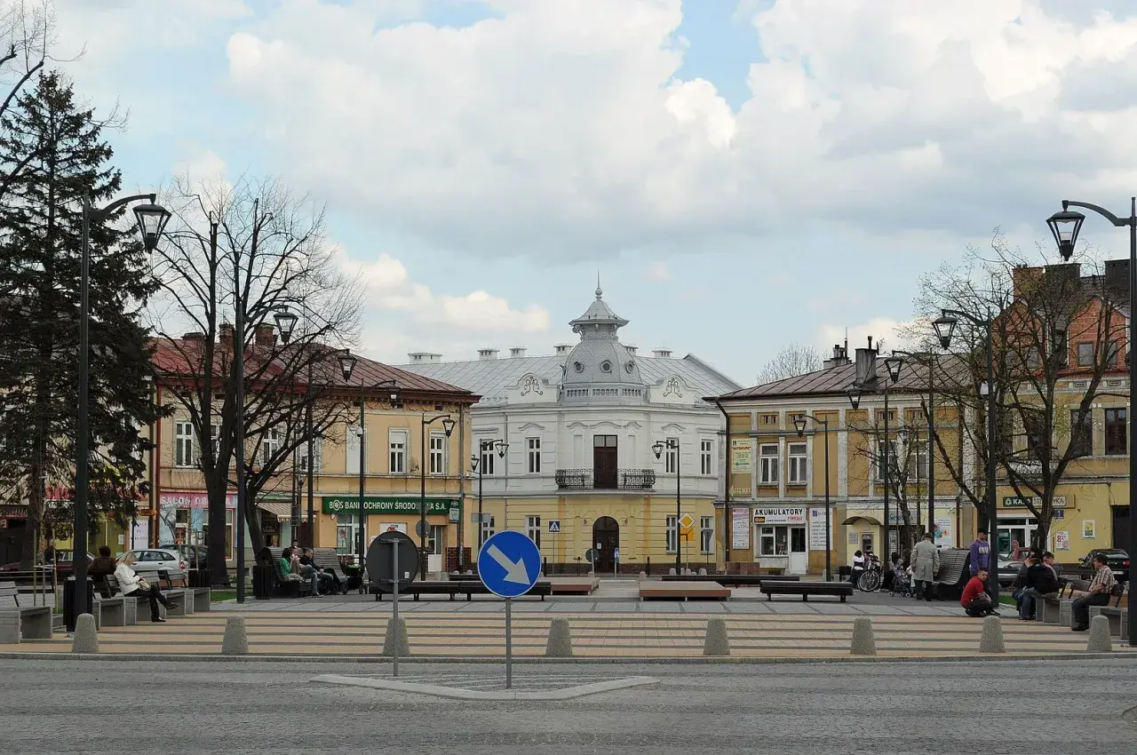 Rynek w Mielcu z kamienicami i ludźmi odpoczywającymi na ławkach. Idealne miejsce na mieleckie atrakcje na weekend.