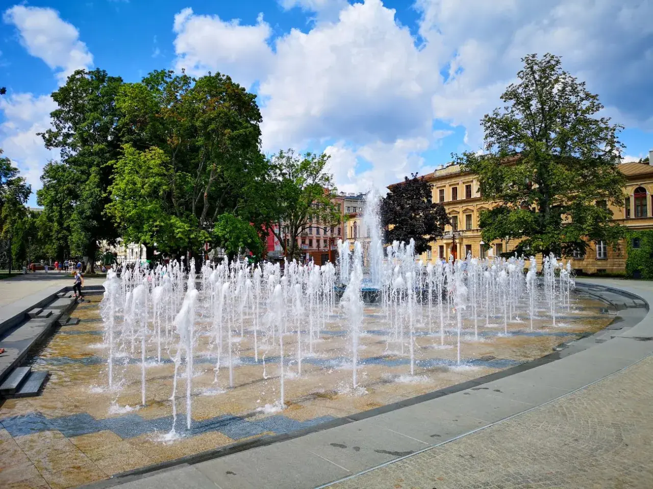 Plac Litewski w Lublinie tętni życiem, a fontanny tworzą wodny taniec na tle zabytkowych kamienic.