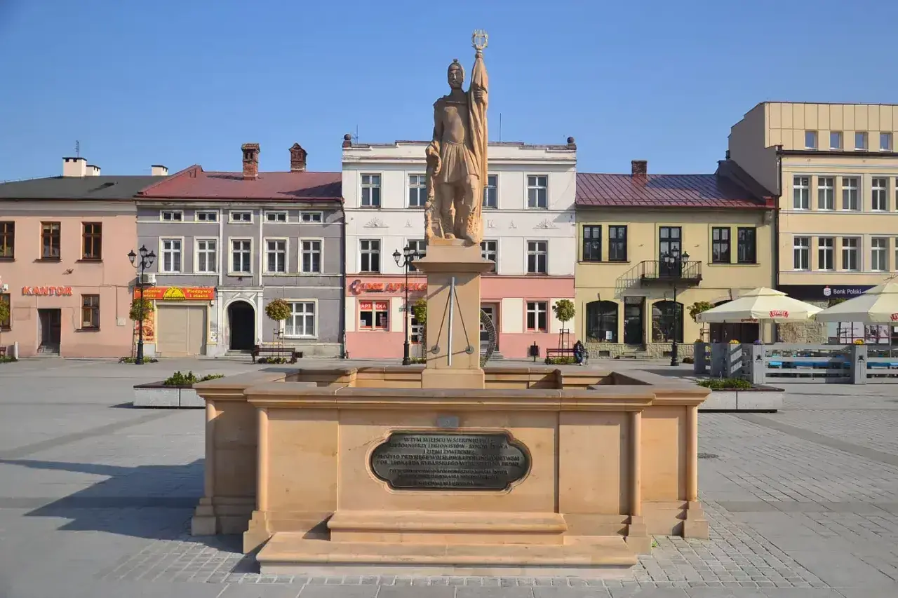 Pomnik na żywiec rynku, z kolorowymi kamienicami w tle.