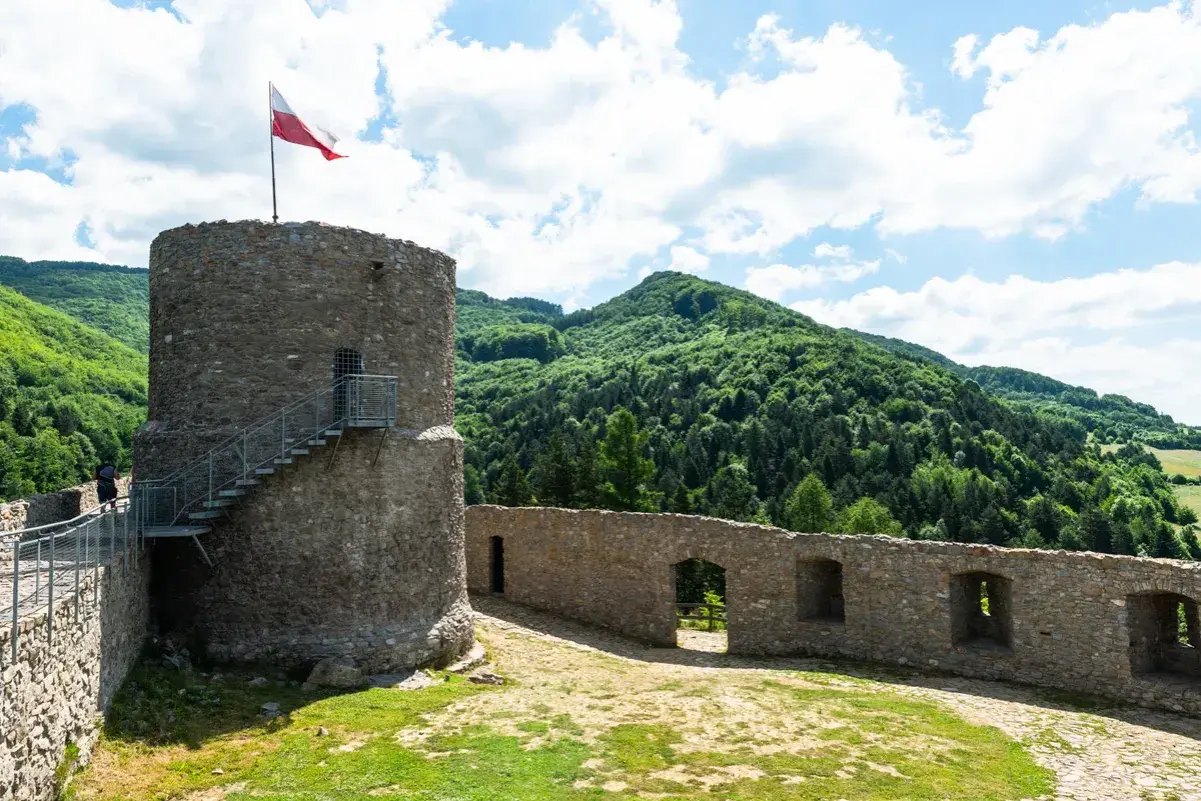 Kamienna wieża z polską flagą i malownicze wzgórza. Rytro atrakcje zachwycają widokami i historią.