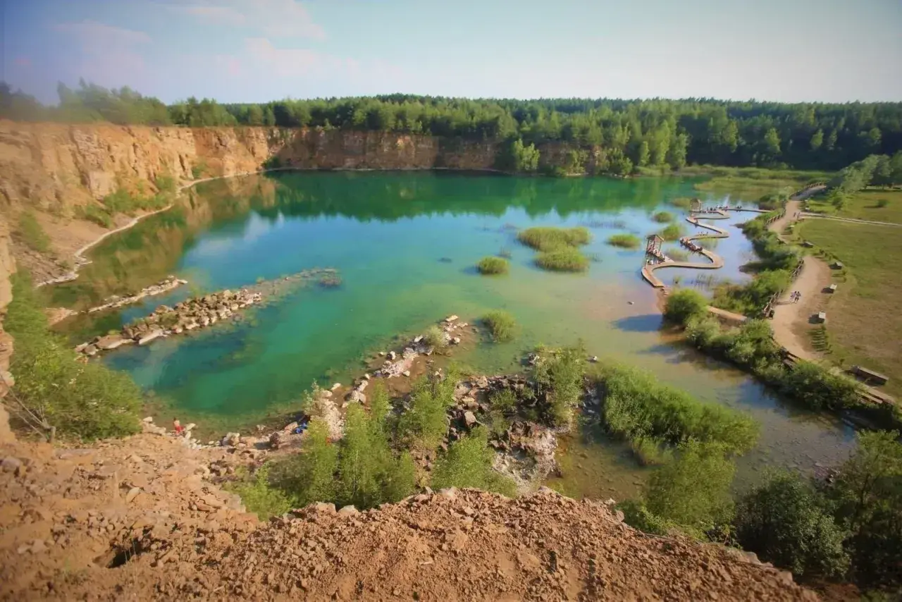 Turkusowe jezioro w Koninie, dawny wyrobisko, z drewnianymi kładkami i zielenią.