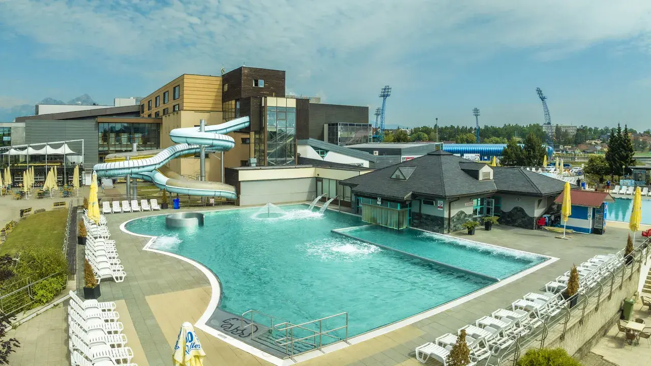 AquaCity Poprad: baseny, zjeżdżalnie wodne i leżaki pod błękitnym niebem.