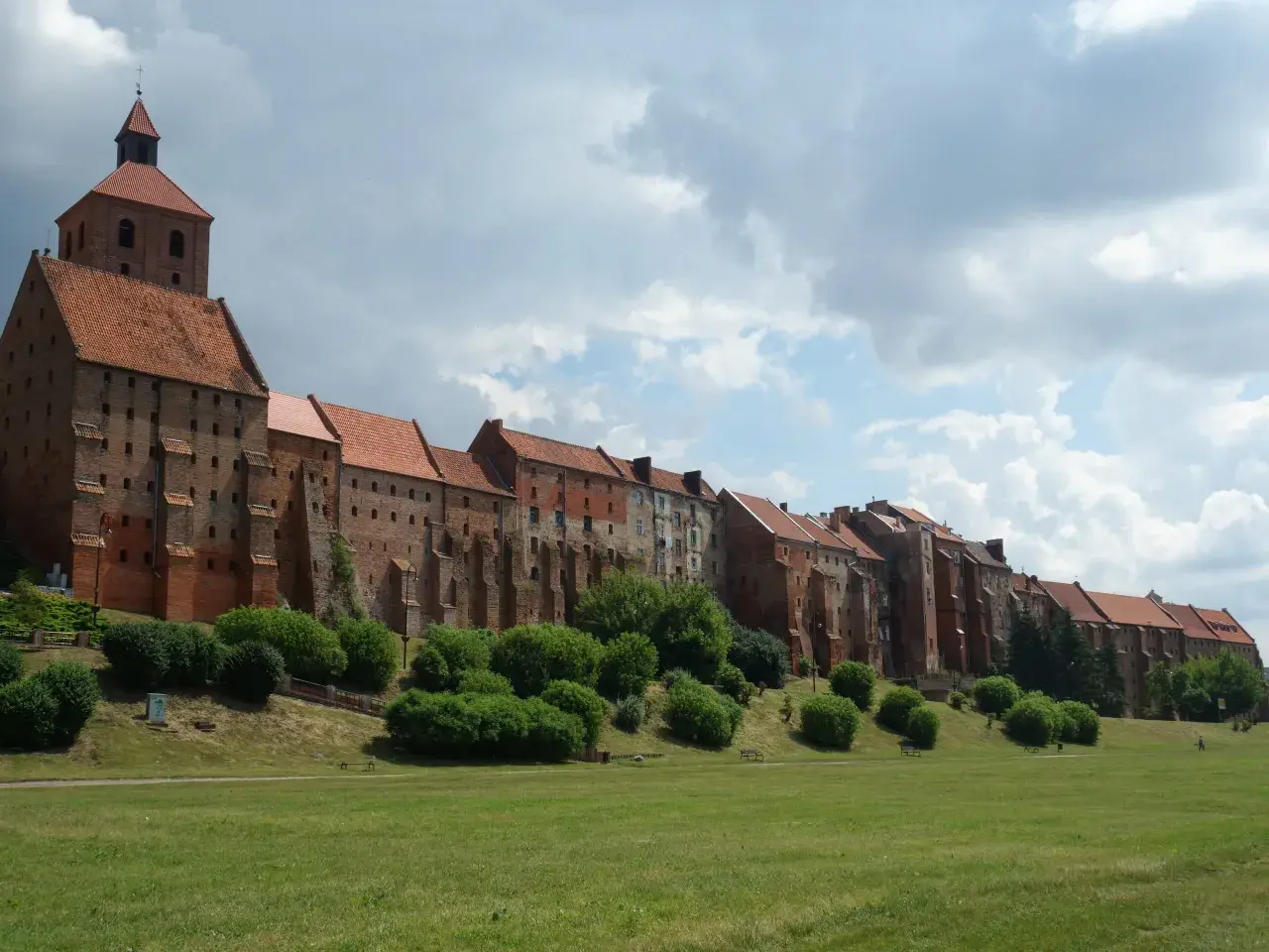 Grudziądz atrakcje na weekend: imponujące spichrze nad Wisłą, zielony teren rekreacyjny i malownicze niebo. Idealne miejsce na spacer.