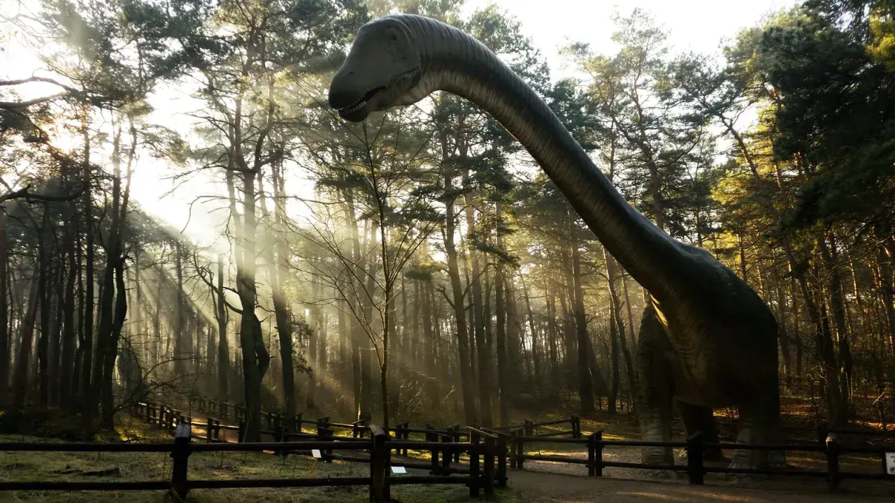 Dinozaur w lesie, jedna z atrakcji Solca Kujawskiego, w promieniach słońca.