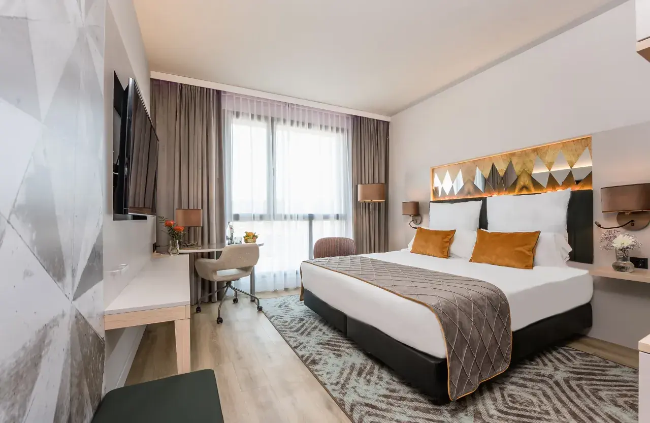 Nowoczesny pokój hotelowy z dużym łóżkiem, biurkiem i telewizorem.