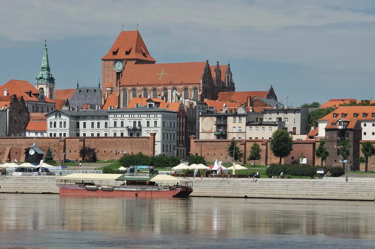 Widok na średniowieczny zespół miejski Torunia z Wisły, z katedrą i ceglanymi murami.