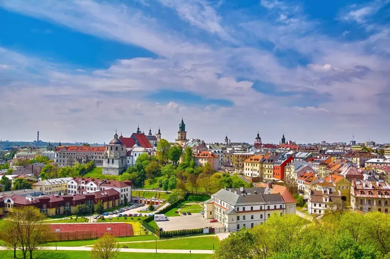 Widok na zabytkowe miasto na Lubelszczyźnie z kościołami i kolorowymi kamienicami pod błękitnym niebem.