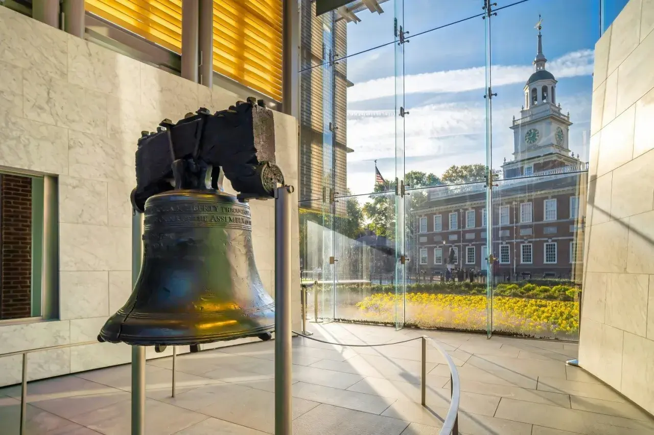 Liberty Bell w nowoczesnym wnętrzu, z widokiem na Independence Hall i kwitnące kwiaty.