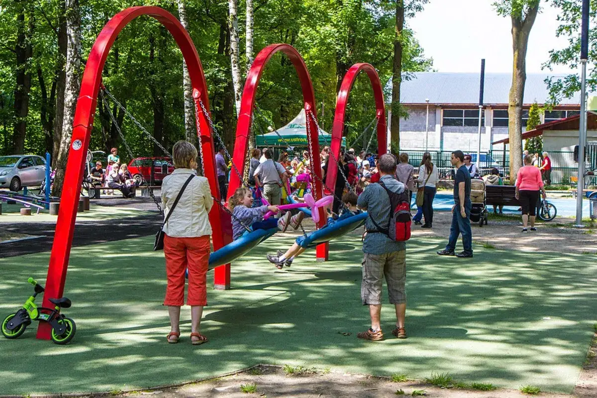 Ustroń atrakcje dzisiaj: dzieci bawią się na huśtawkach w parku, dorośli obserwują.