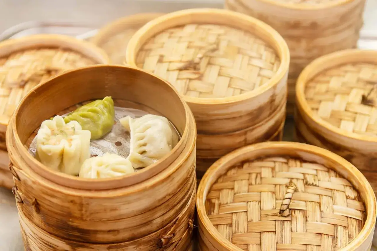 Parujące koszyczki bambusowe pełne różnorodnych pierożków dim sum. Smaczna uczta czeka!