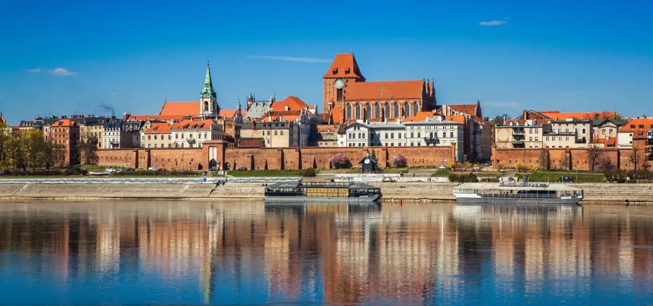 Widok na zabytkowe miasto z ceglanymi murami obronnymi i kościołami, odbijające się w spokojnej rzece. Spacer po bulwarze filadelfijskim to podróż w czasie.