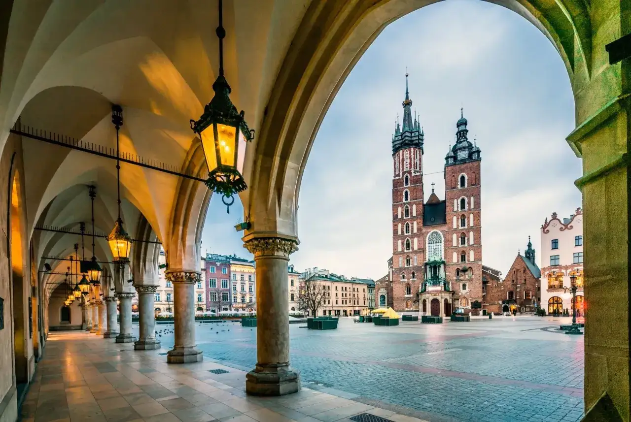 Podcienia Sukiennic w Krakowie, z widokiem na Kościół Mariacki. Stare miasto w Krakowie oświetlone latarniami.