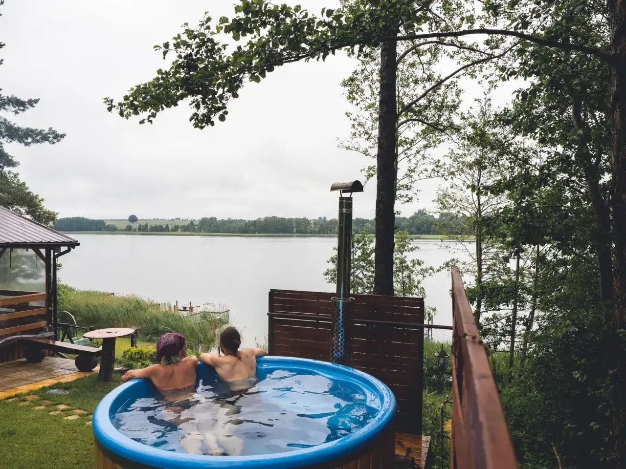 Dwie osoby relaksują się w balii z widokiem na jezioro skarlińskie.