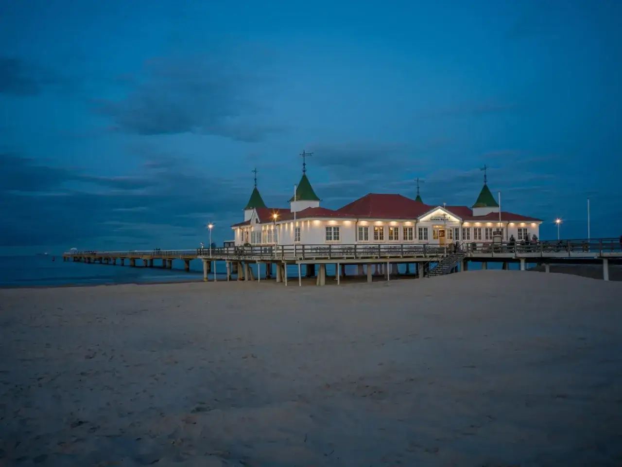 Molo w Ahlbecku, oświetlone wieczorem, to jedna z głównych atrakcji tego nadmorskiego kurortu. Piękny widok na morze i plażę.