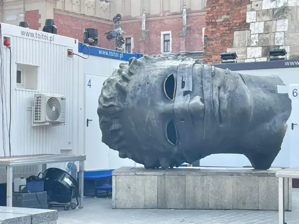 Monumentalna głowa na rynku w Krakowie, z pustymi oczodołami, wygląda jakby patrzyła w dal.